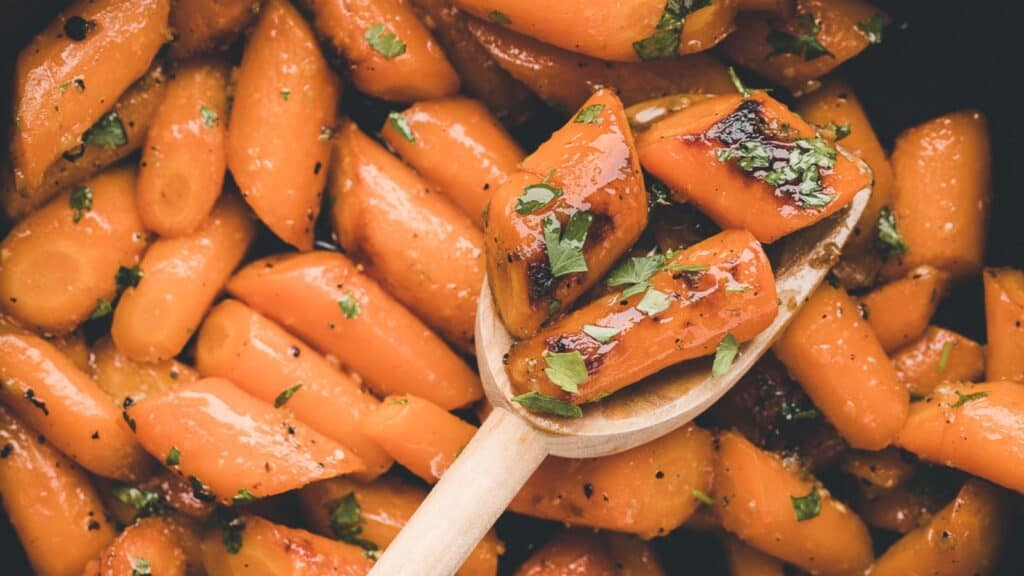 Healthy recipes: Roasted carrots in a pan with a wooden spoon.