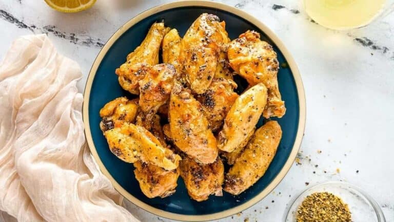 Grilled chicken wings on a blue plate with lemons and spices.