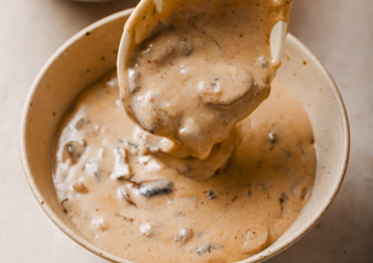 A bowl of Hungarian mushroom soup with a gold spoon.