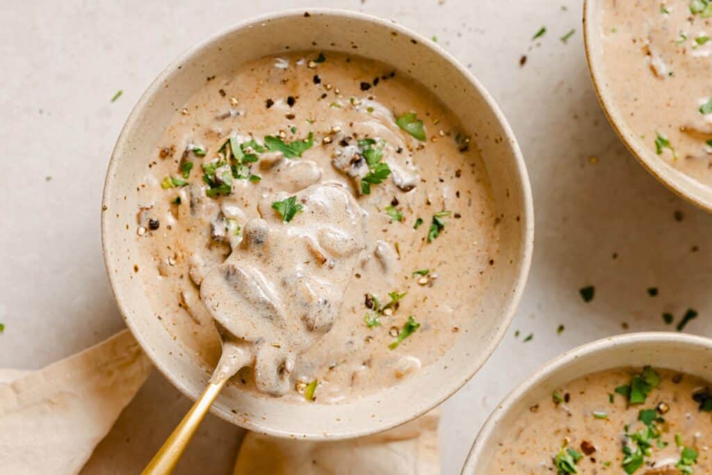 Three bowls of mushroom soup on a table.