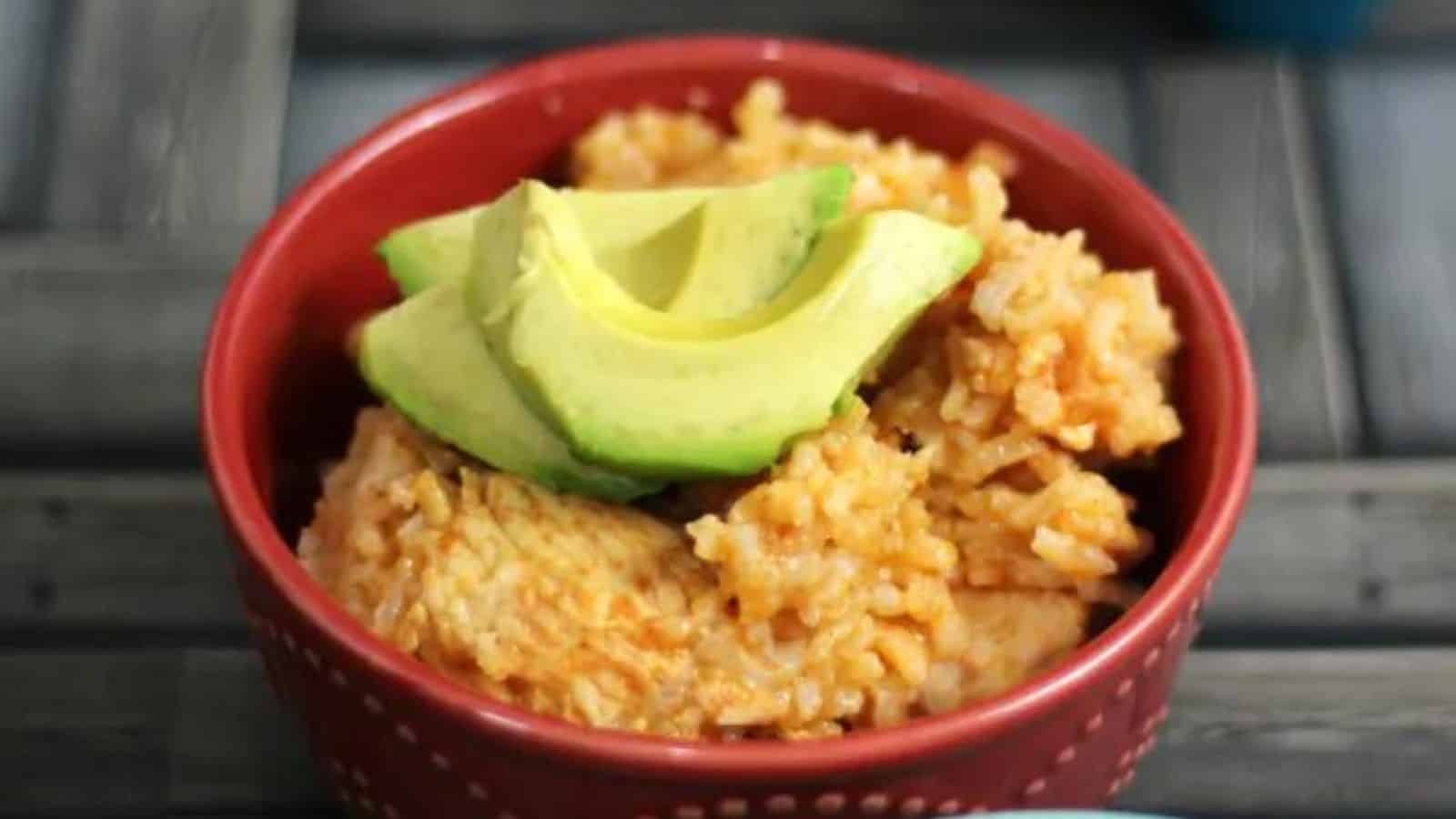 Picture of chicken and rice in a red bowl topped with avocado slices.