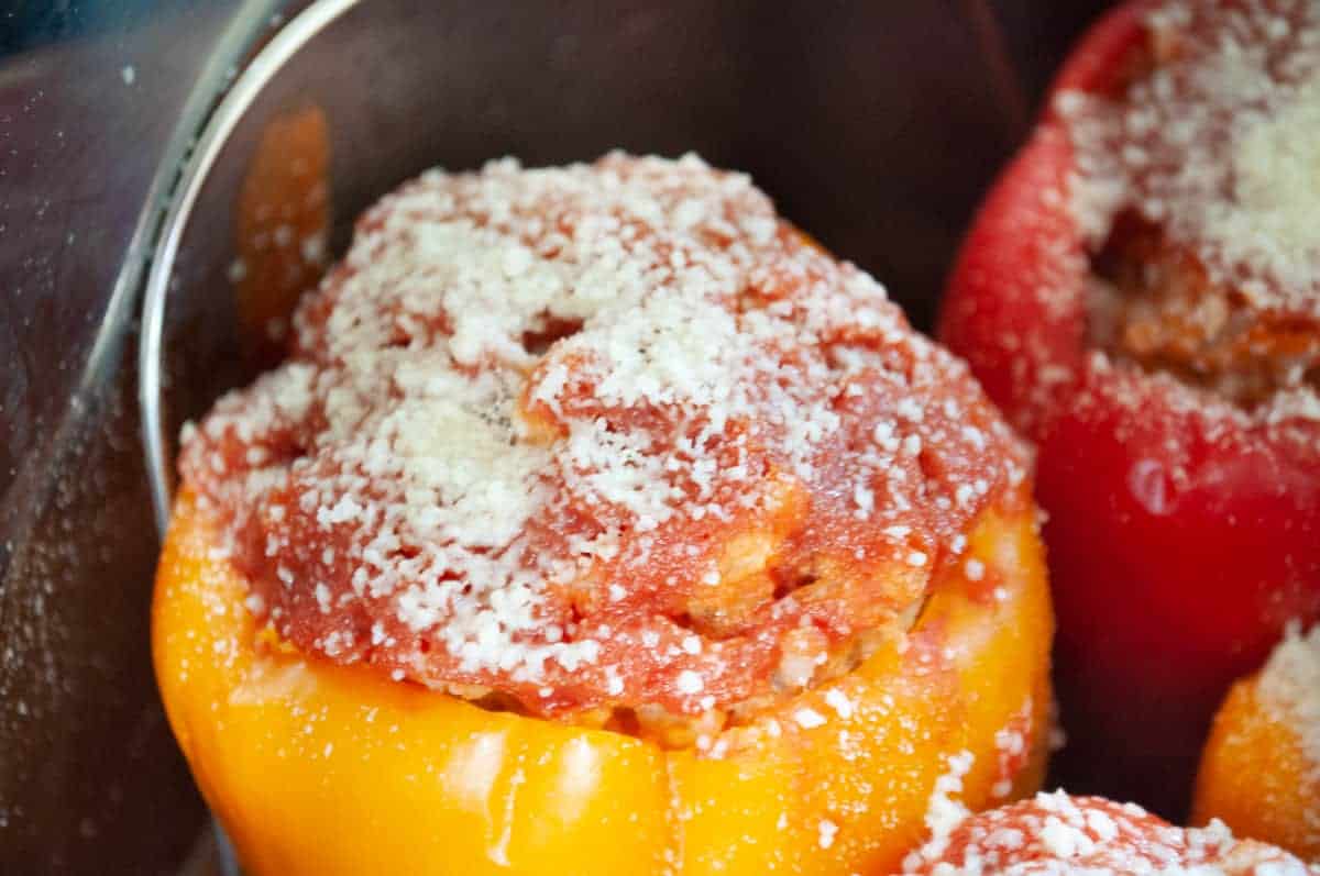 Stuffed peppers topped with sauce and cheese in the instant pot. 