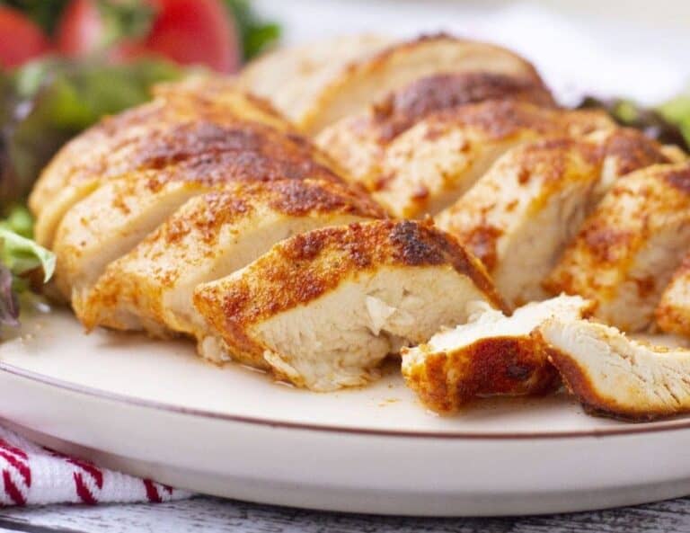 Chicken breasts on a plate with salad and tomatoes.