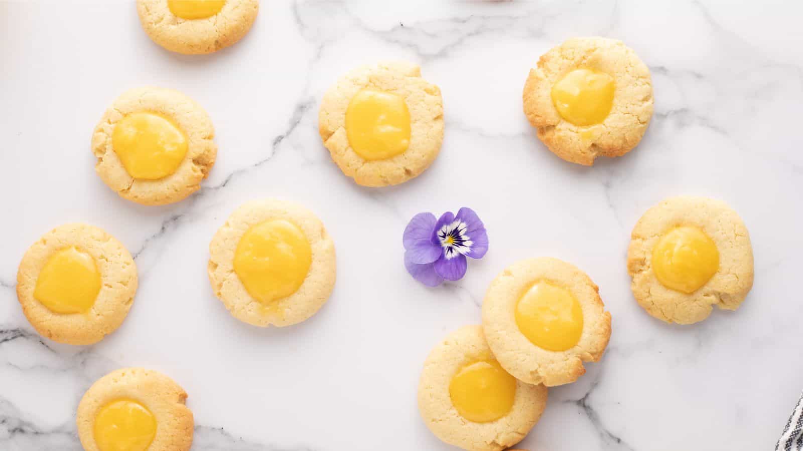 Lemon curd cookies on a marble table with a purple flower.