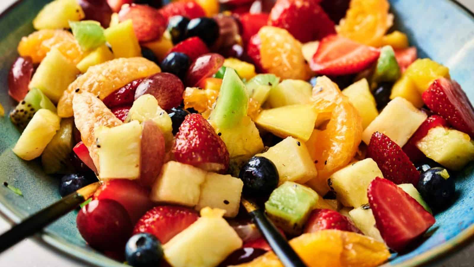 Fruit salad in a blue bowl with a spoon.