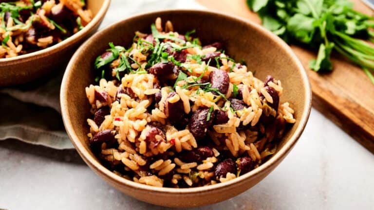 Two bowls of rice and beans on a cutting board.