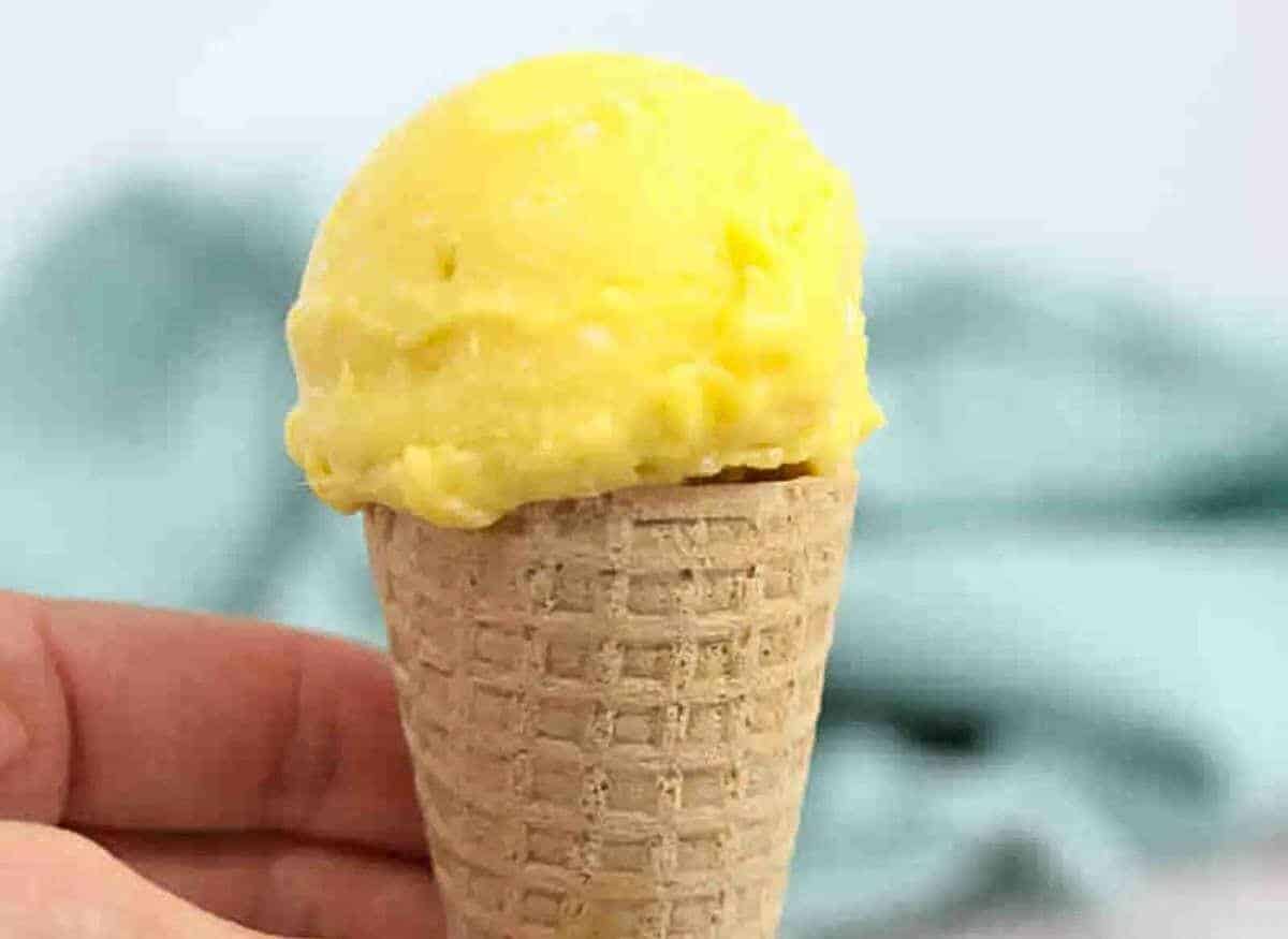 A person holding a yellow ice cream cone.