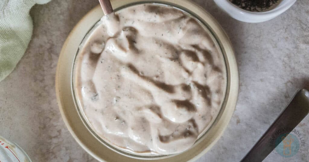 A bowl of dressing with a spoon next to it.