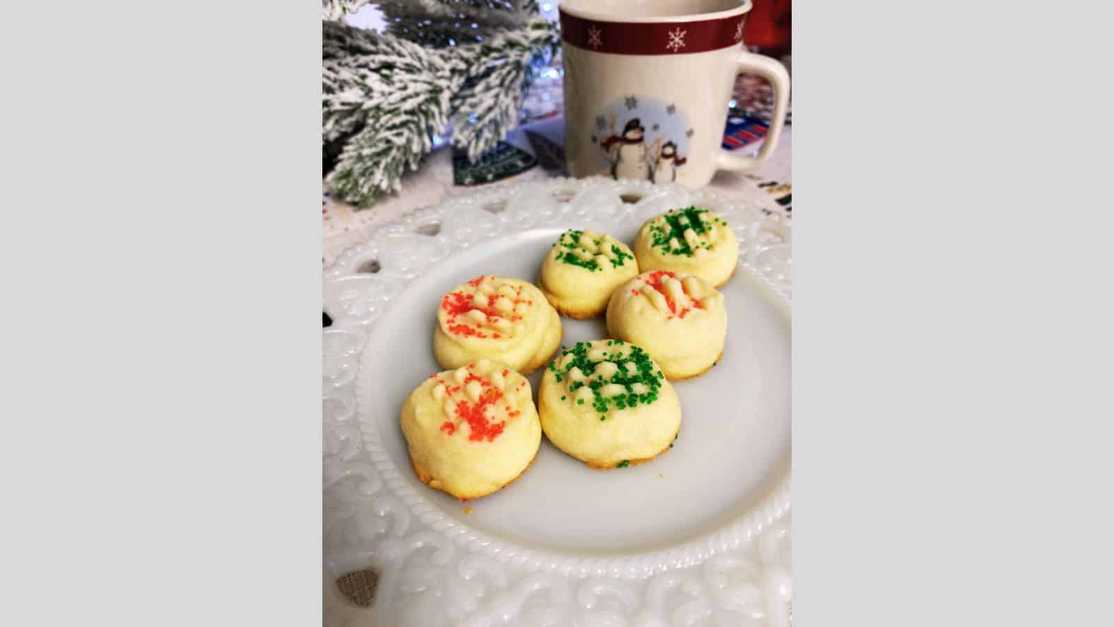 Melting moments cookies on white plate with snowman mug in background.