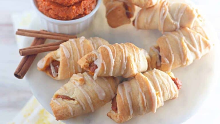 Pumpkin cinnamon crescent rolls with dipping sauce on a plate.