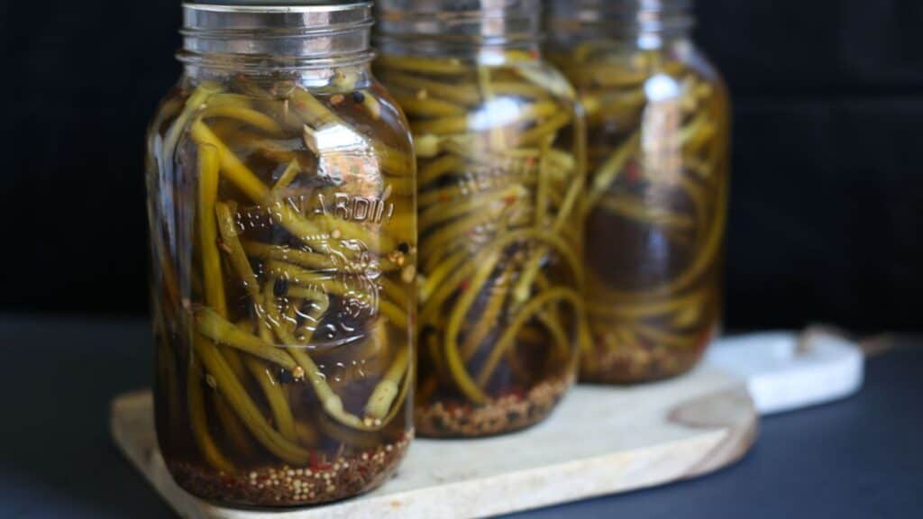 Three jars of pickled vegetables, including 17 Gut-Friendly Recipes, on a wooden cutting board.