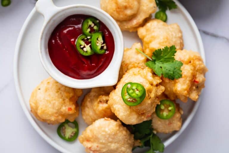 Fried calamari with dipping sauce on a white plate.