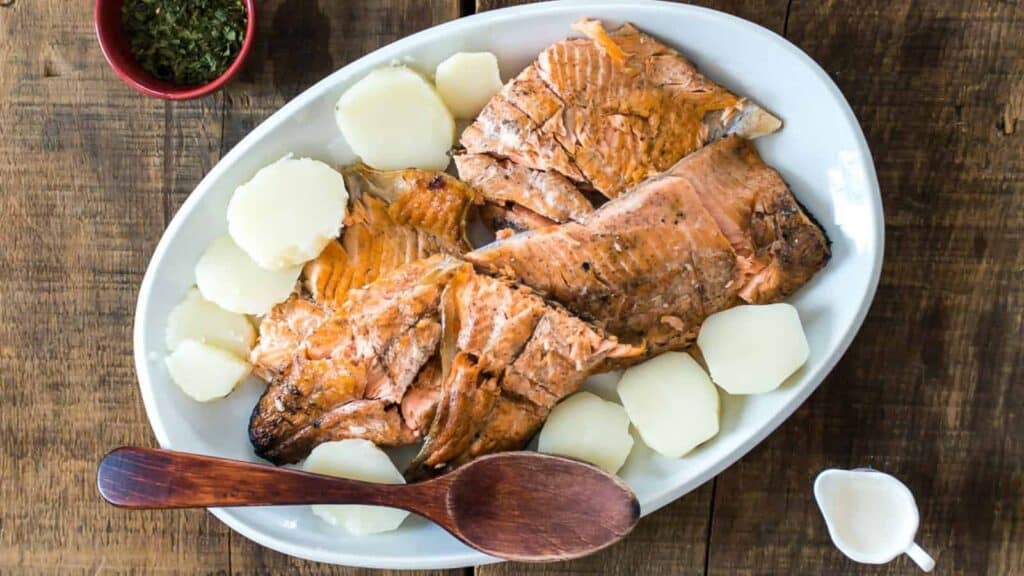 Grilled salmon with potatoes on a white plate.
