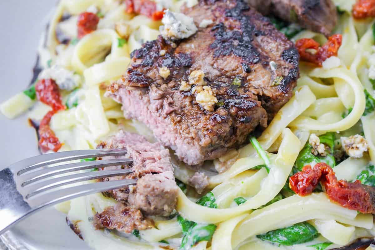 A Copycat Olive Garden dish featuring Steak Gorgonzola served with pasta and spinach.