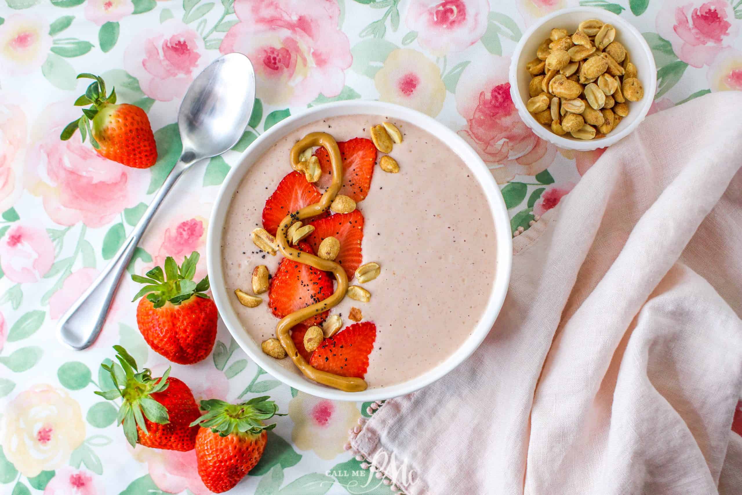 Smoothie  topped with strawberries, peanuts, and peanut butter swirl in bowl.