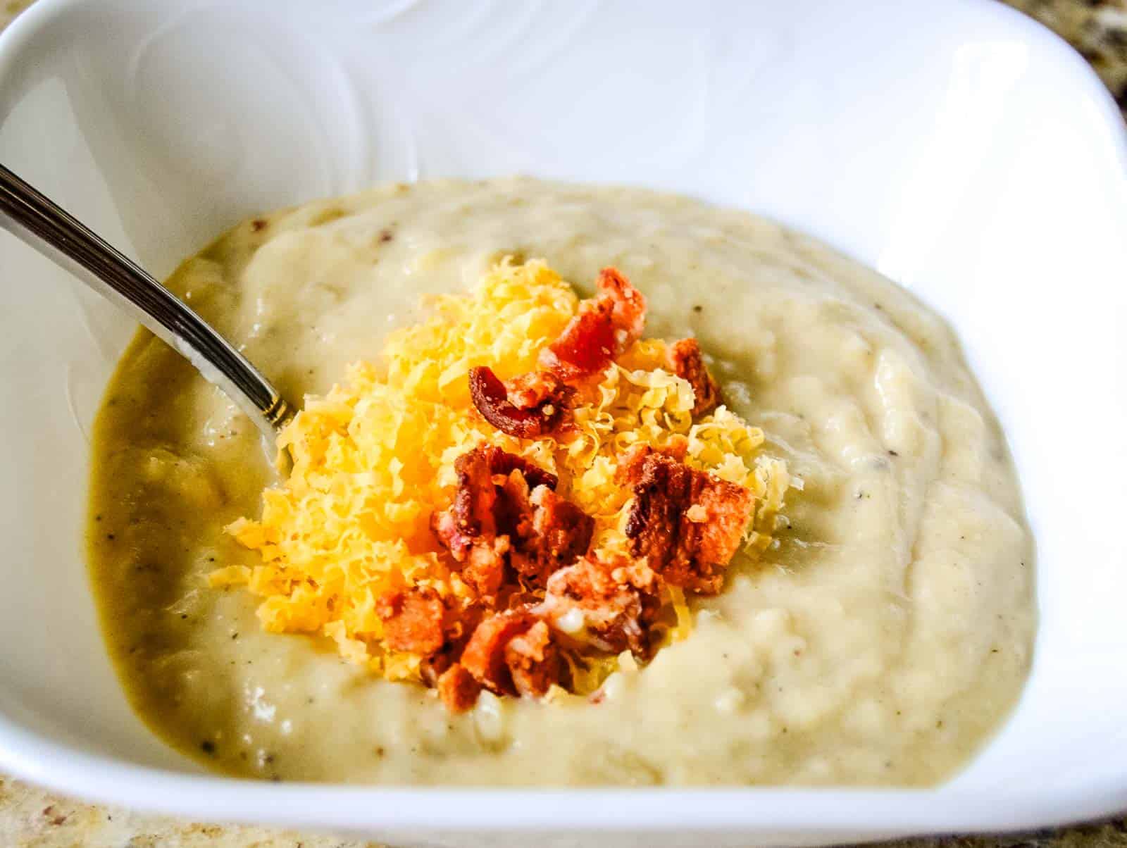A bowl of loaded parsnip potato soup topped with bacon and cheddar cheese.