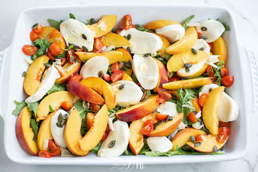 Sliced peaches, tomatoes, and fresh mozzarella slices on a tray.