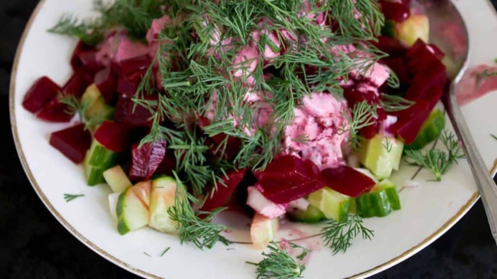 Cucumbers and beets with dill in bowl.