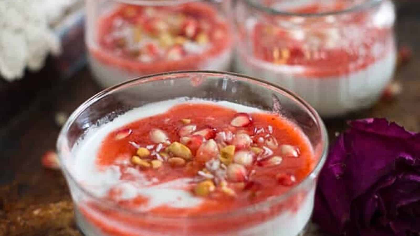 A glass of pomegranate yogurt with pomegranate seeds.