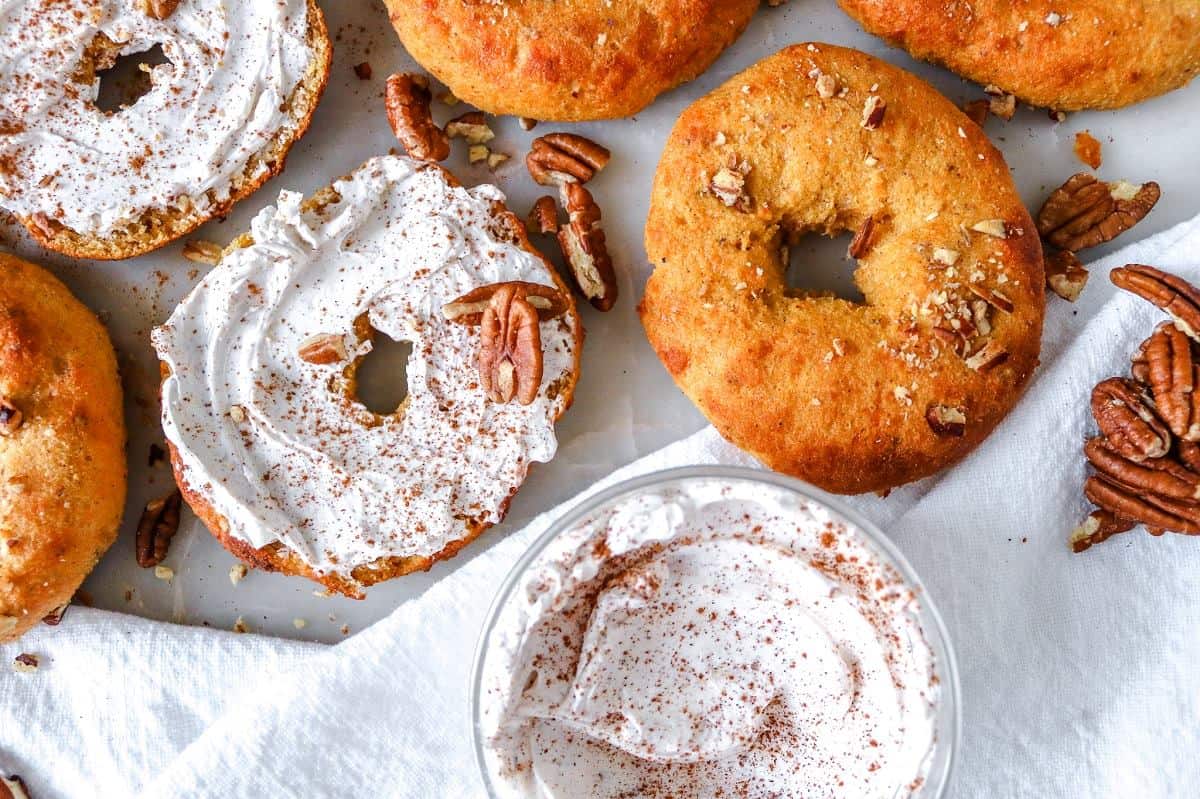 A table of bagels with icing and pecans.