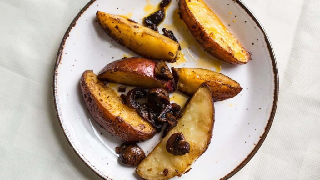 Roasted potatoes and mushrooms on a white plate.