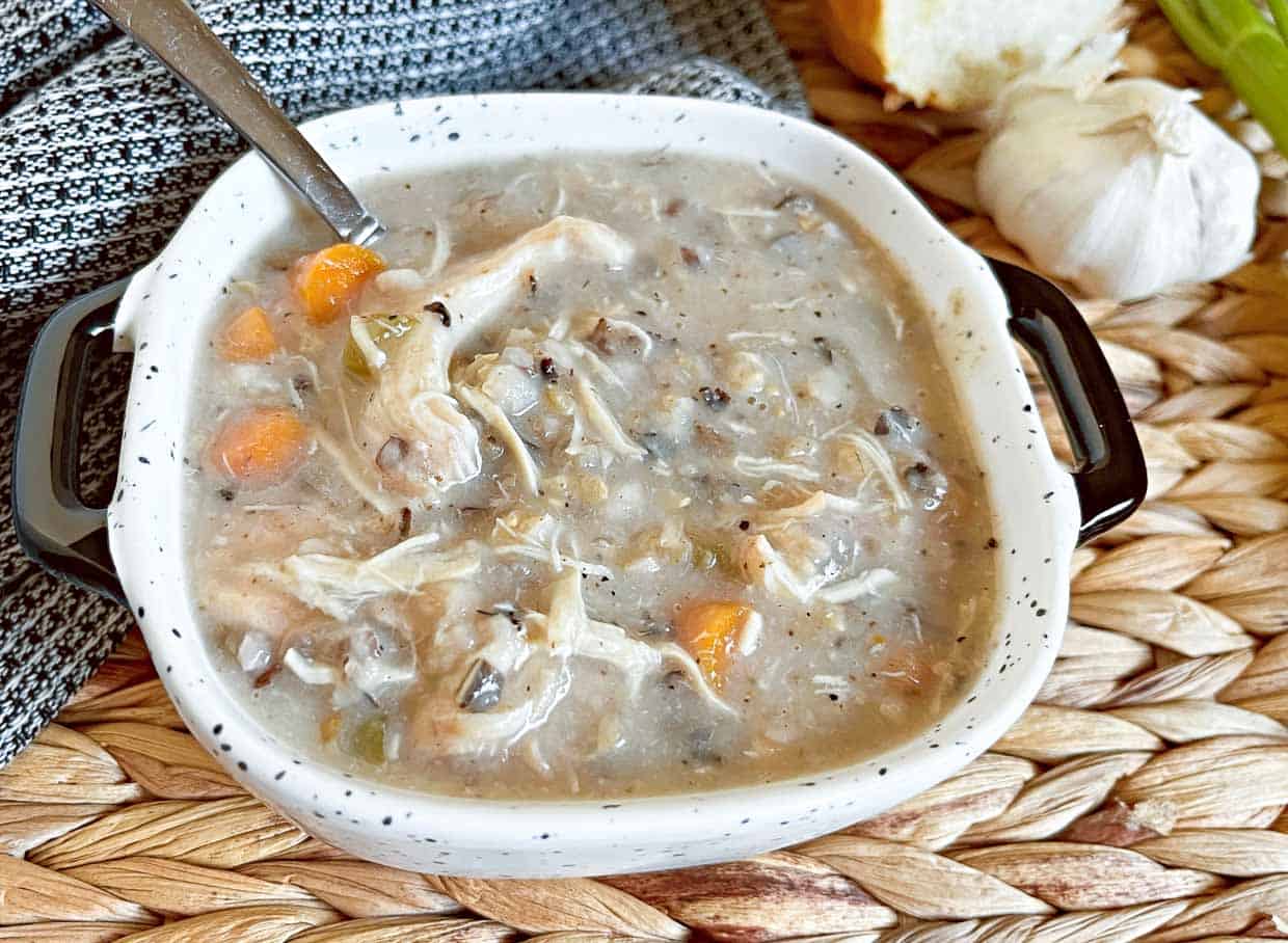 A bowl of chicken and wild rice soup with a spoon.