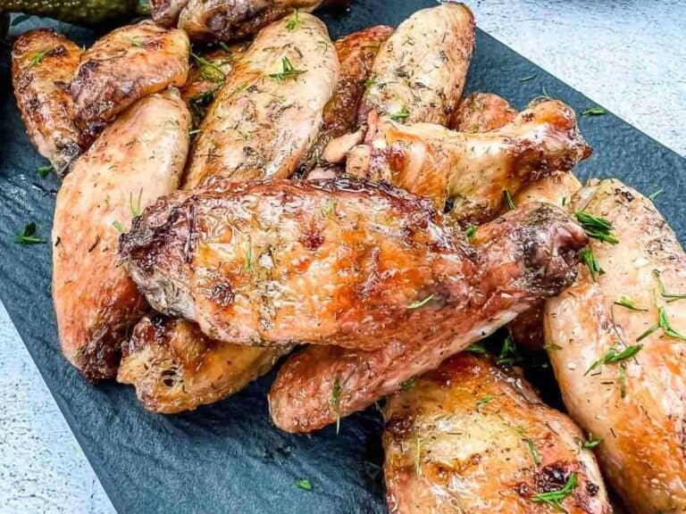 Smoked dill pickle wings on a black plate.