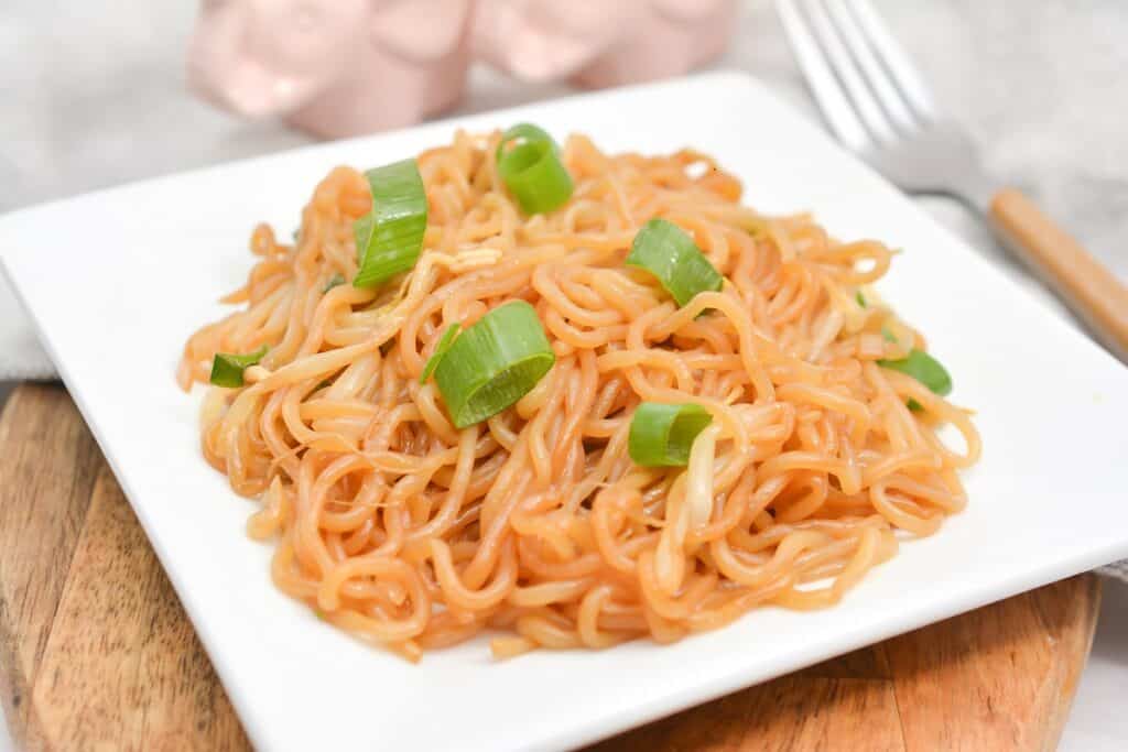 A plate of noodles with green onions and a fork.
