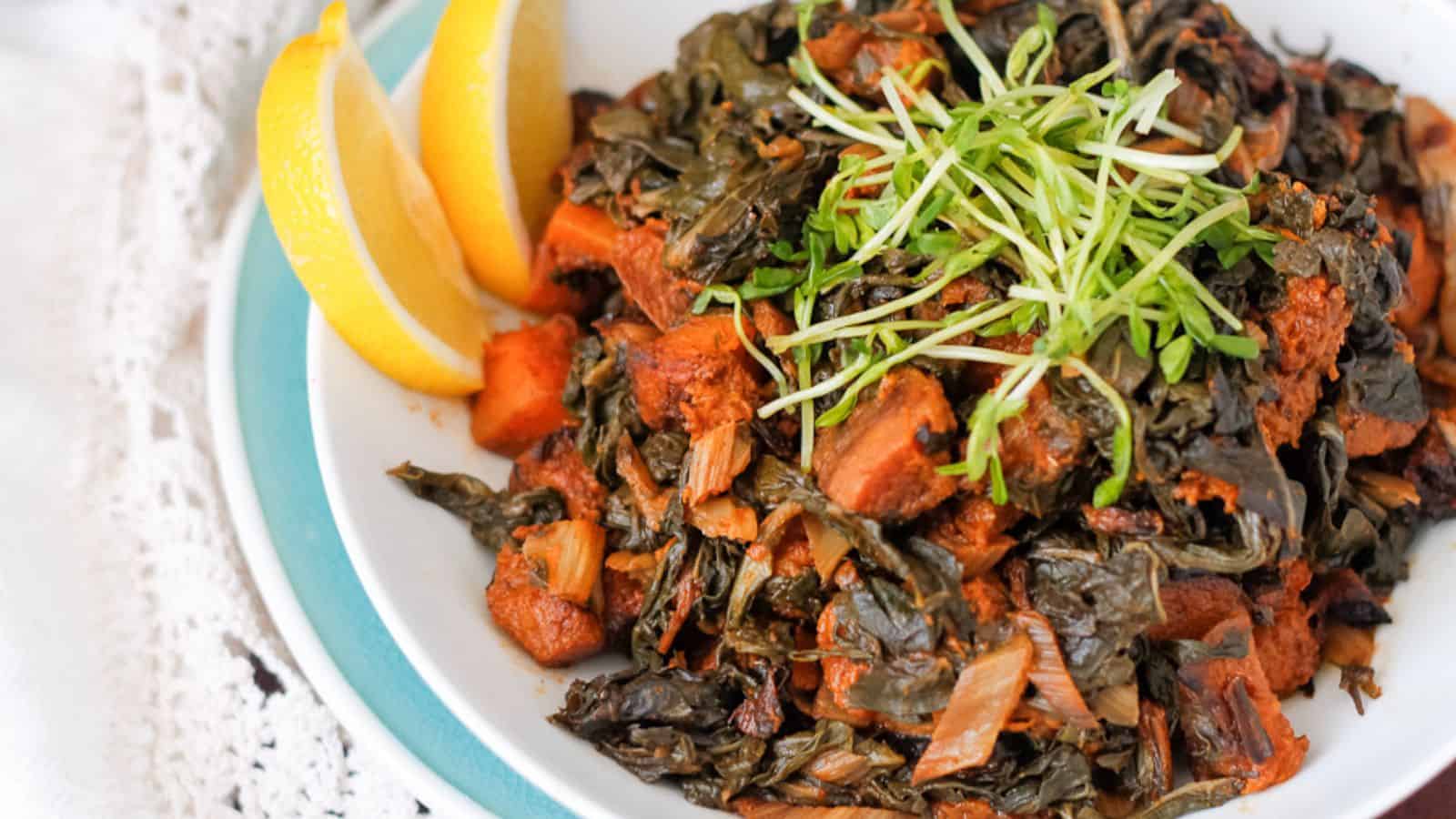 A bowl of greens with a lemon wedge on top.