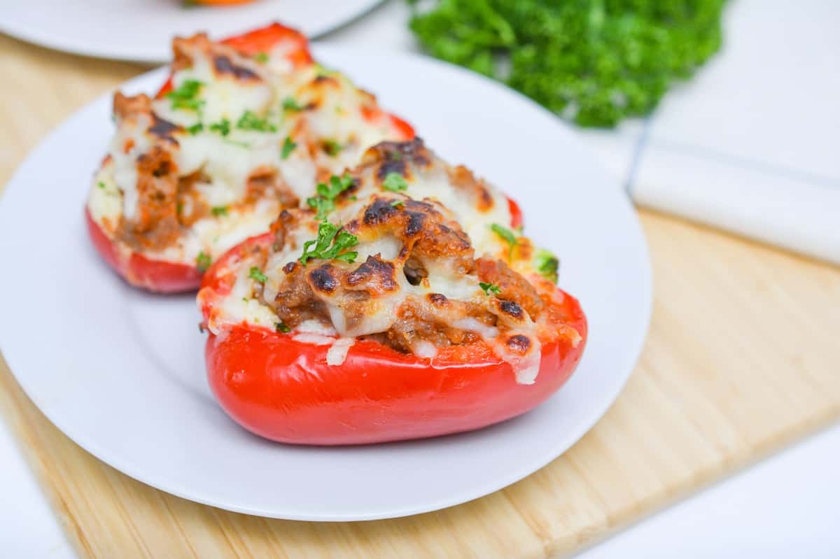 Two stuffed peppers with cheese on a plate.