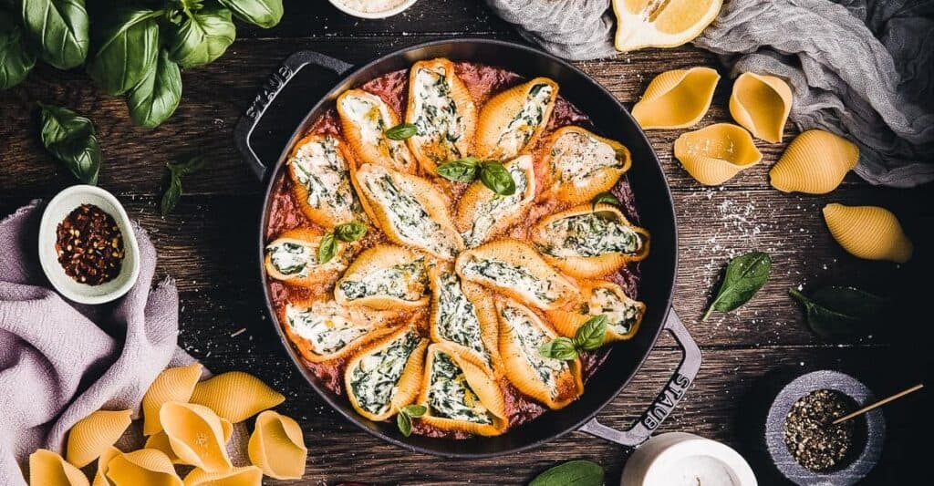 Cheesy stuffed shells with spinach and cheese on a wooden table.