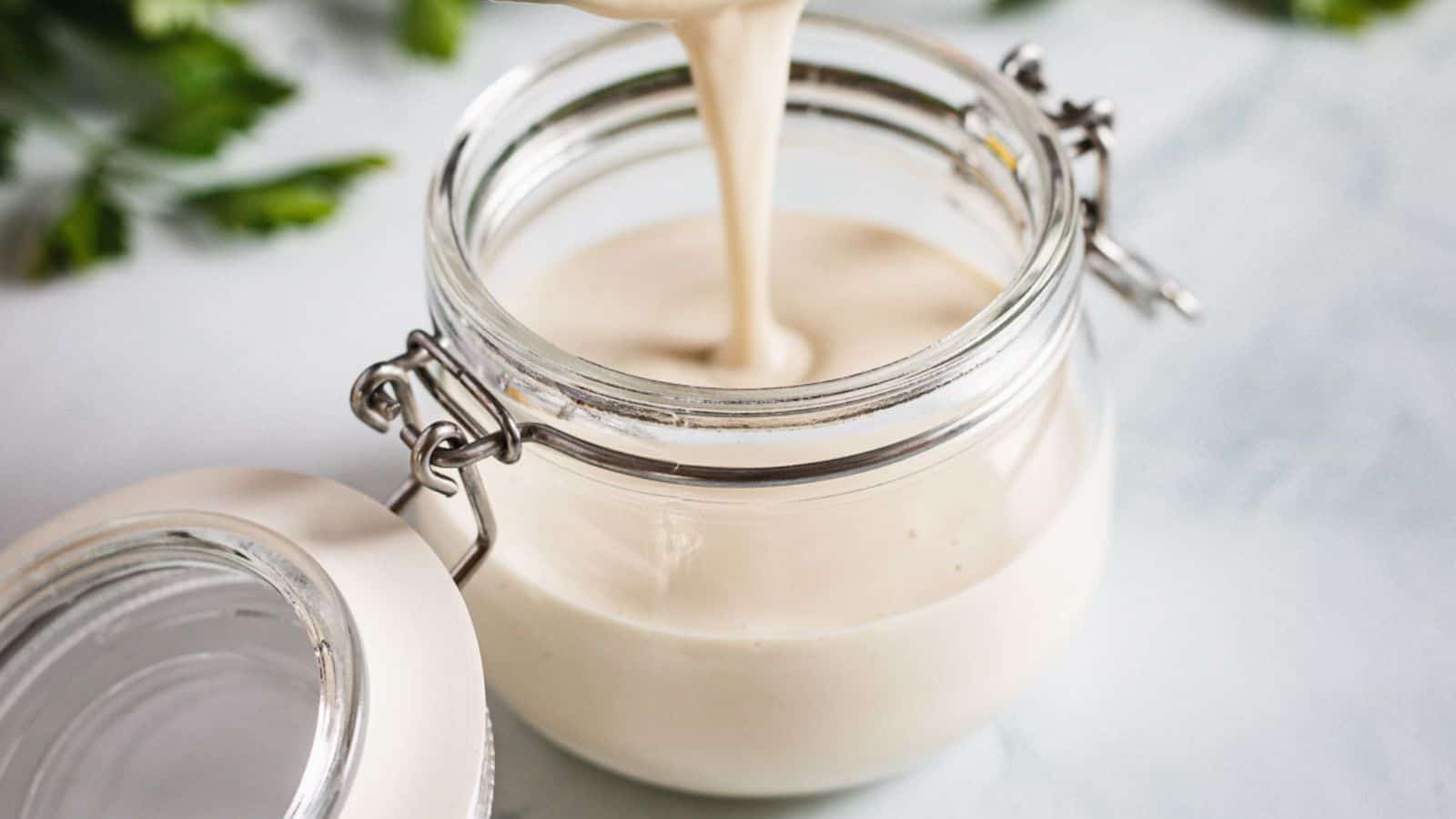 A jar with a white sauce pouring out of it.