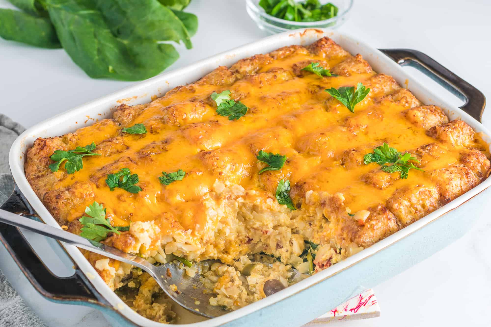 Breakfast casserole with veggies and tator tots in a casserole dish.