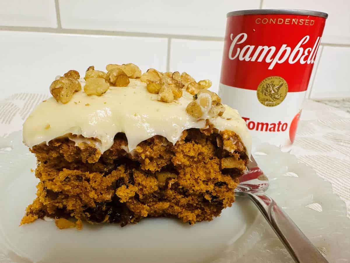 A piece of cake is sitting on a plate next to a can of soup.