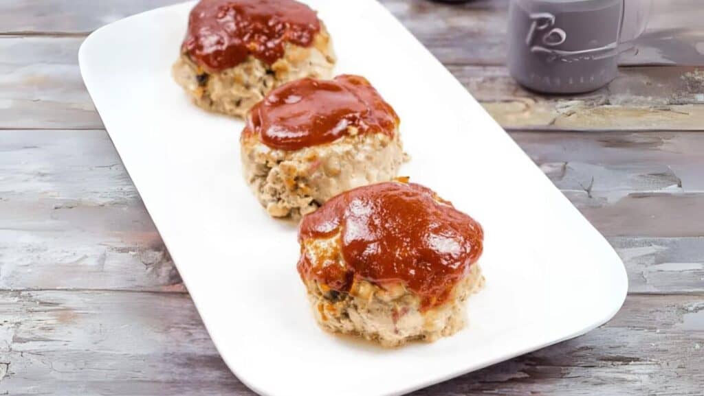 3 Mini Meatloaves in a line on a white plate.