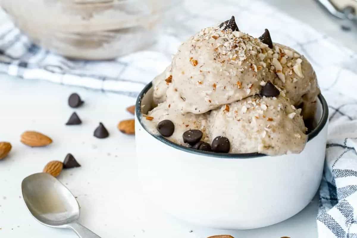 A bowl of ice cream with chocolate chips and almonds.