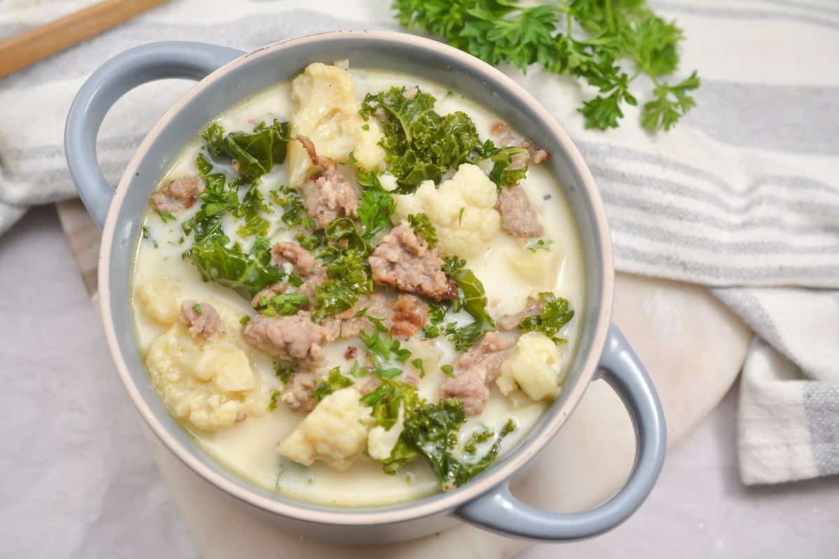 A bowl of soup with meat and kale.