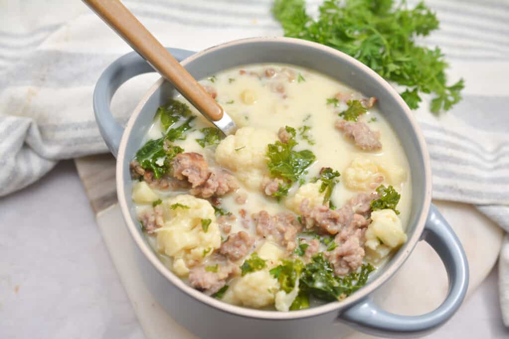 A bowl of soup with meat and kale.