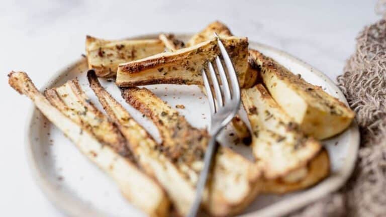 Roasted parsnips on a plate with a fork.