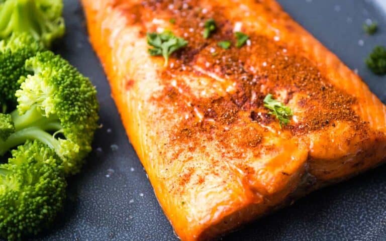 A piece of salmon and broccoli on a plate.