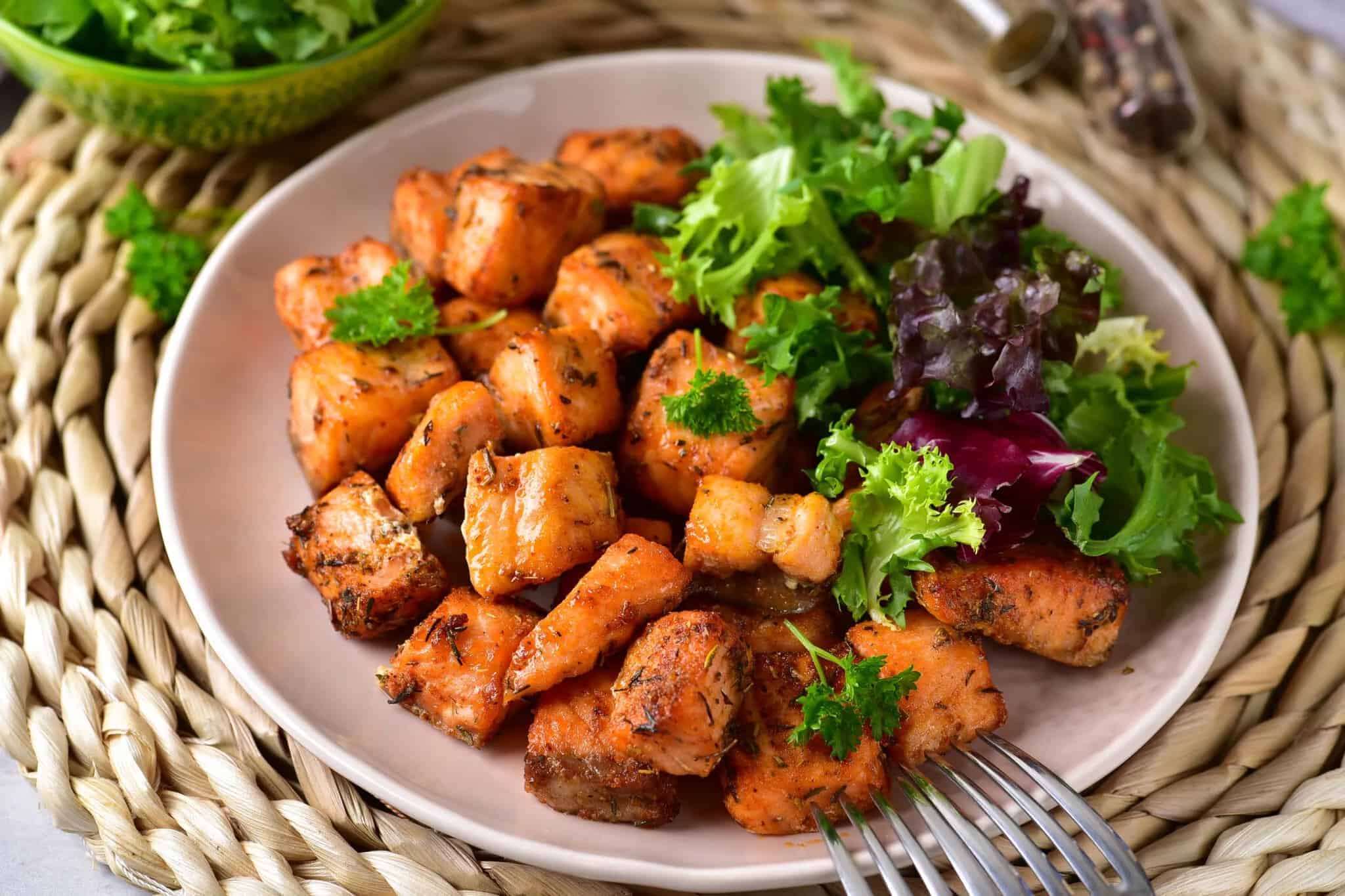 Air Fryer Salmon Bites and a salad on a plate with a fork.