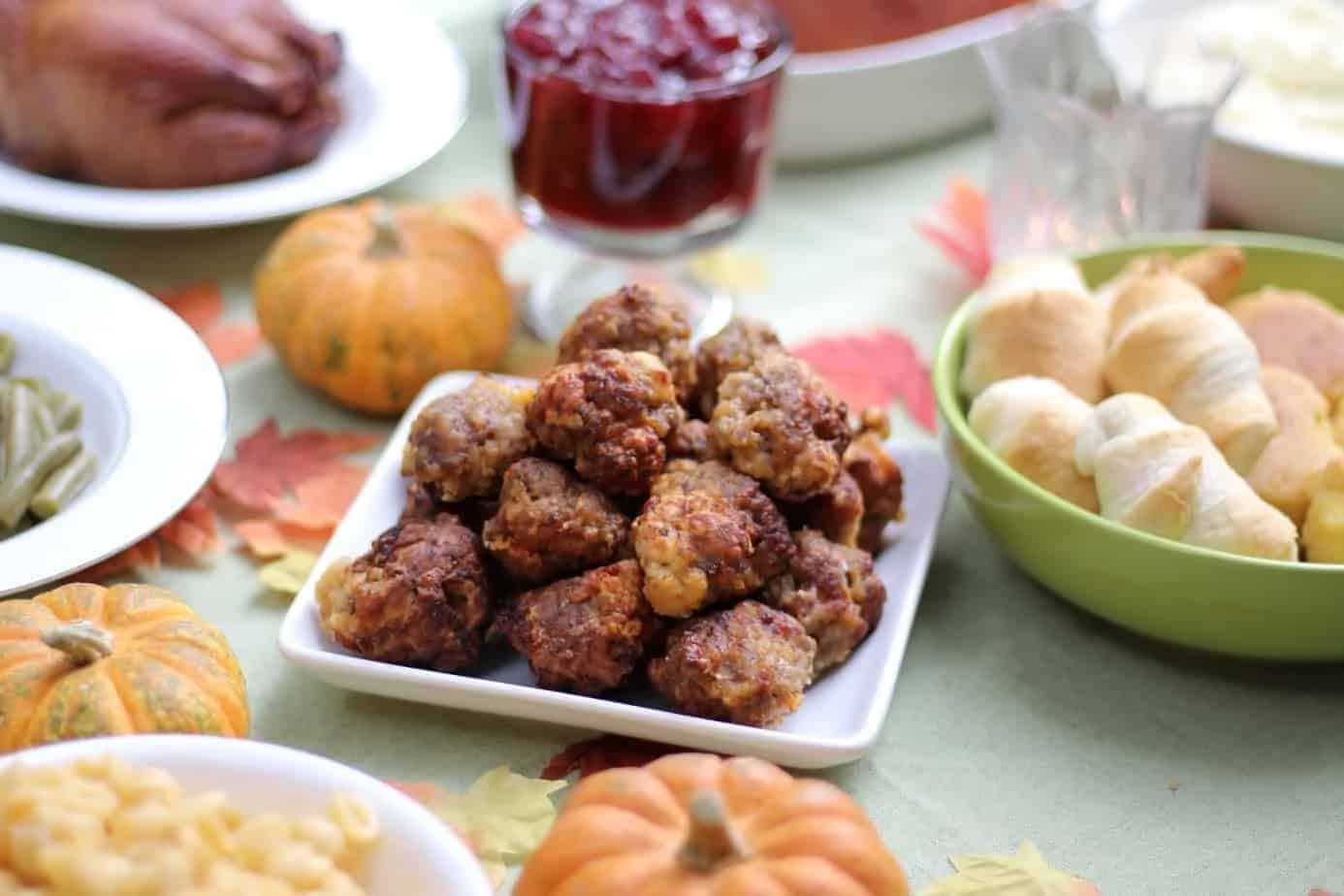 White plate of sausage balls on a Thanksgiving themed table.