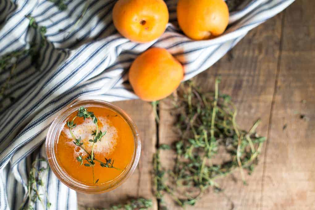 Overhead of apricot jam with apricots and thyme.