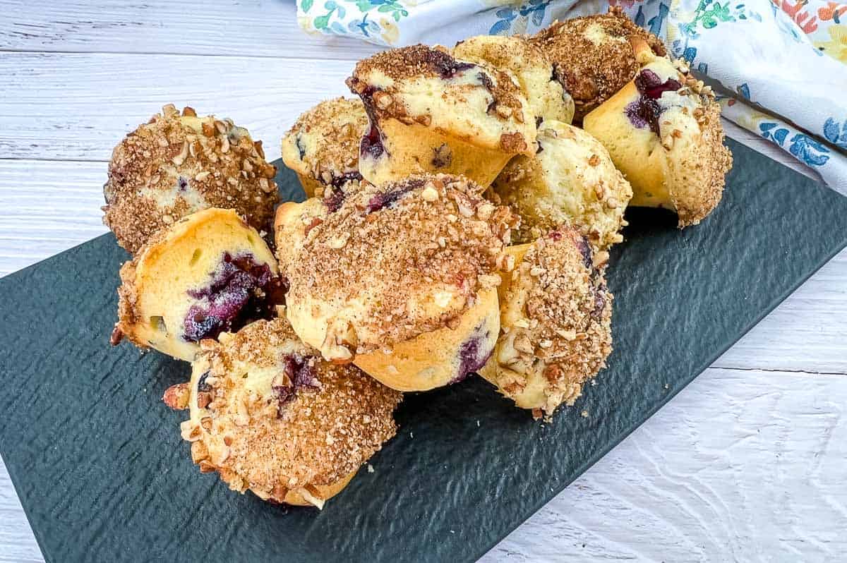 Blueberry Rhubarb Muffins on a black plate with one muffin cut in half.