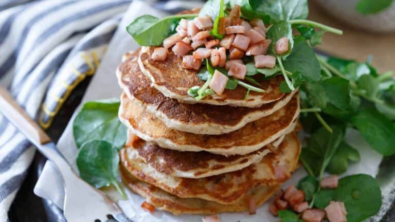 A stack of pancakes with ham and spinach.