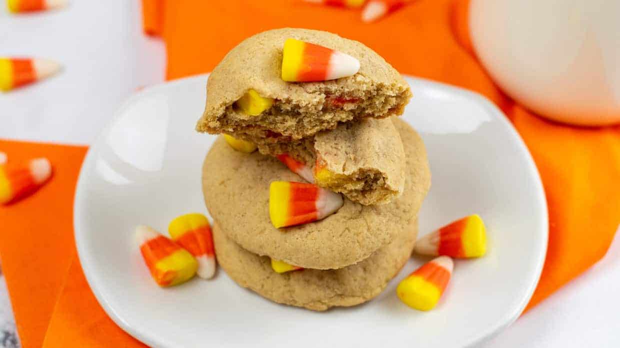 A stack of candy corn cookies on a white plate.