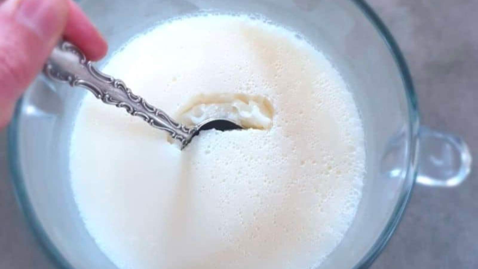 A person scooping cheesecake pudding out of a glass bowl.