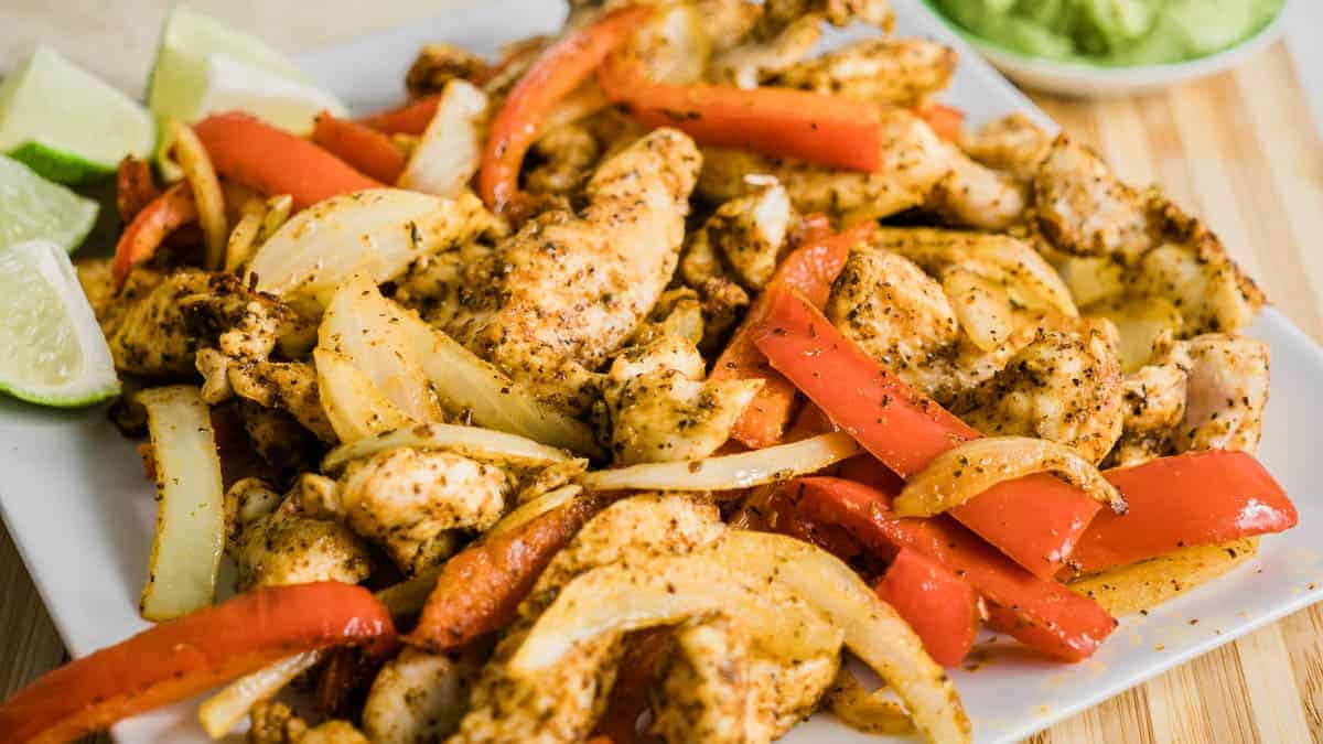 Plate of chicken fajitas with chicken, red bell peppers and onion.