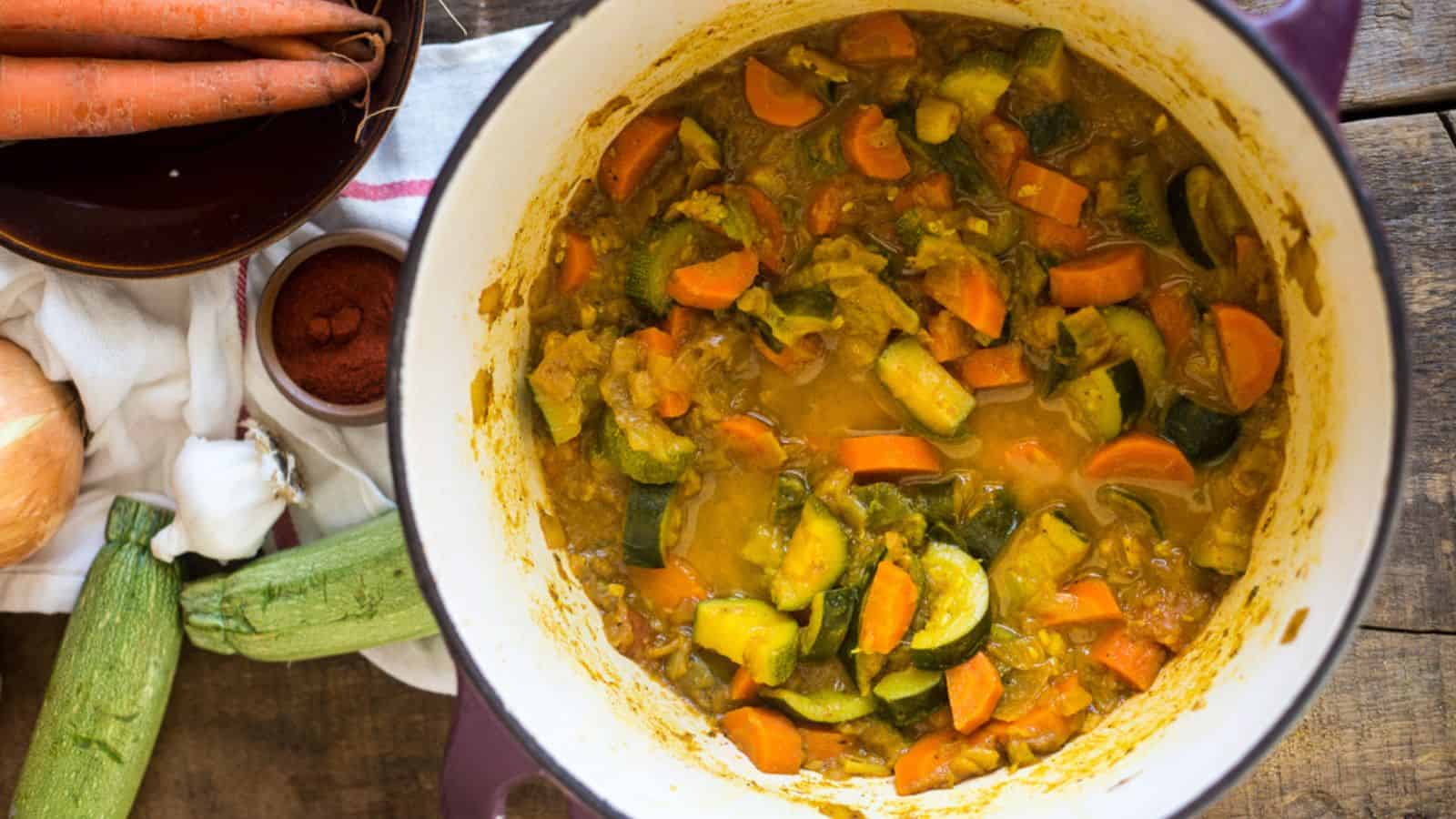 A pot of vegetable stew on a wooden table.