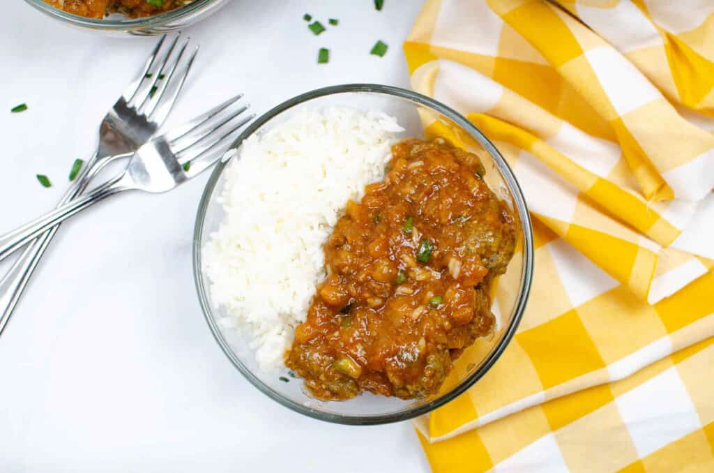 A bowl of curry and rice on a yellow checkered tablecloth.